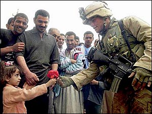 A, Iraqi girl gives a flower to an American soldier